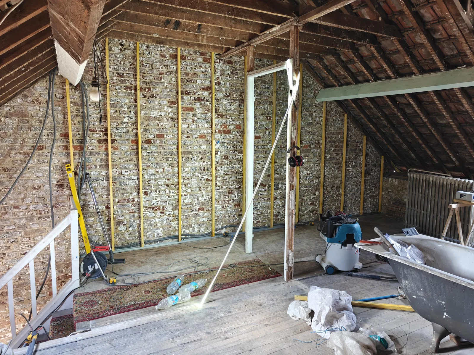 Ossature en tasseaux verticaux fixée sur le mur ancien, légèrement décalée pour isoler aussi derrière.